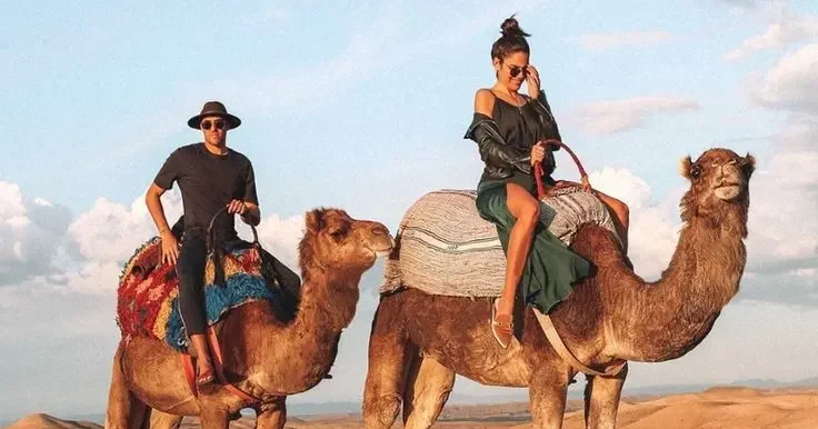 Tourists riding camels through the Agafay desert during sunset.
