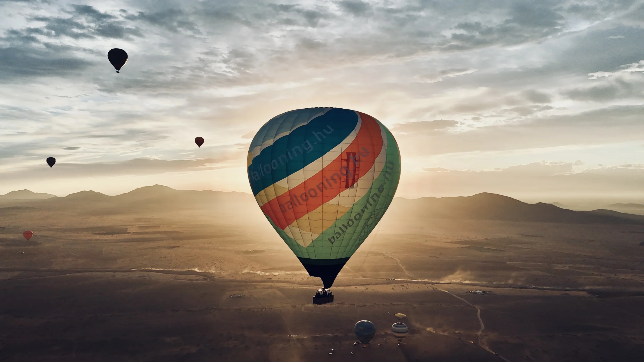 Hot air balloons flying over the Agafay desert during sunrise.