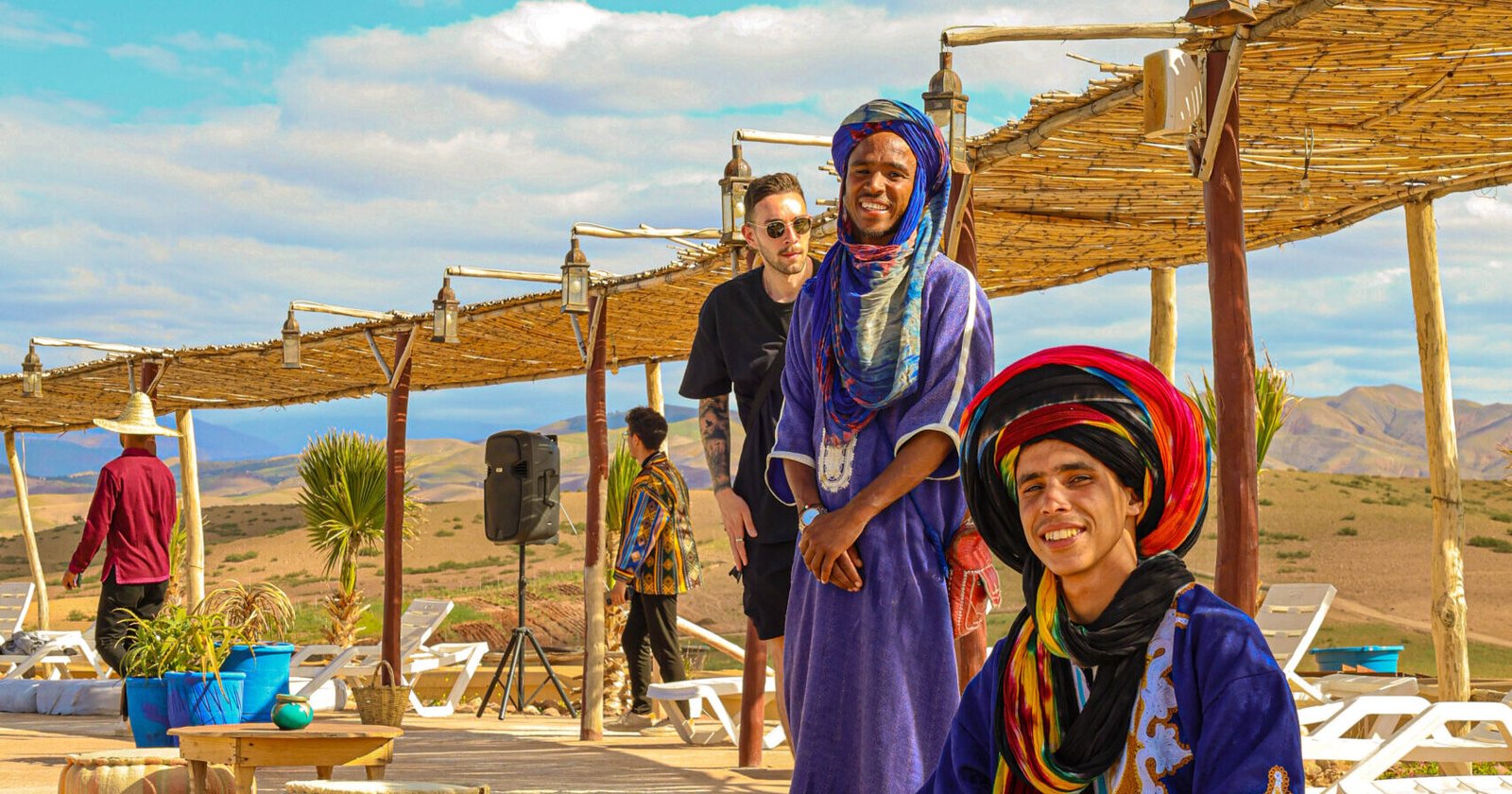 Traditional Moroccan tea ceremony in Agafay Desert with smiling hosts in colorful Berber attire.