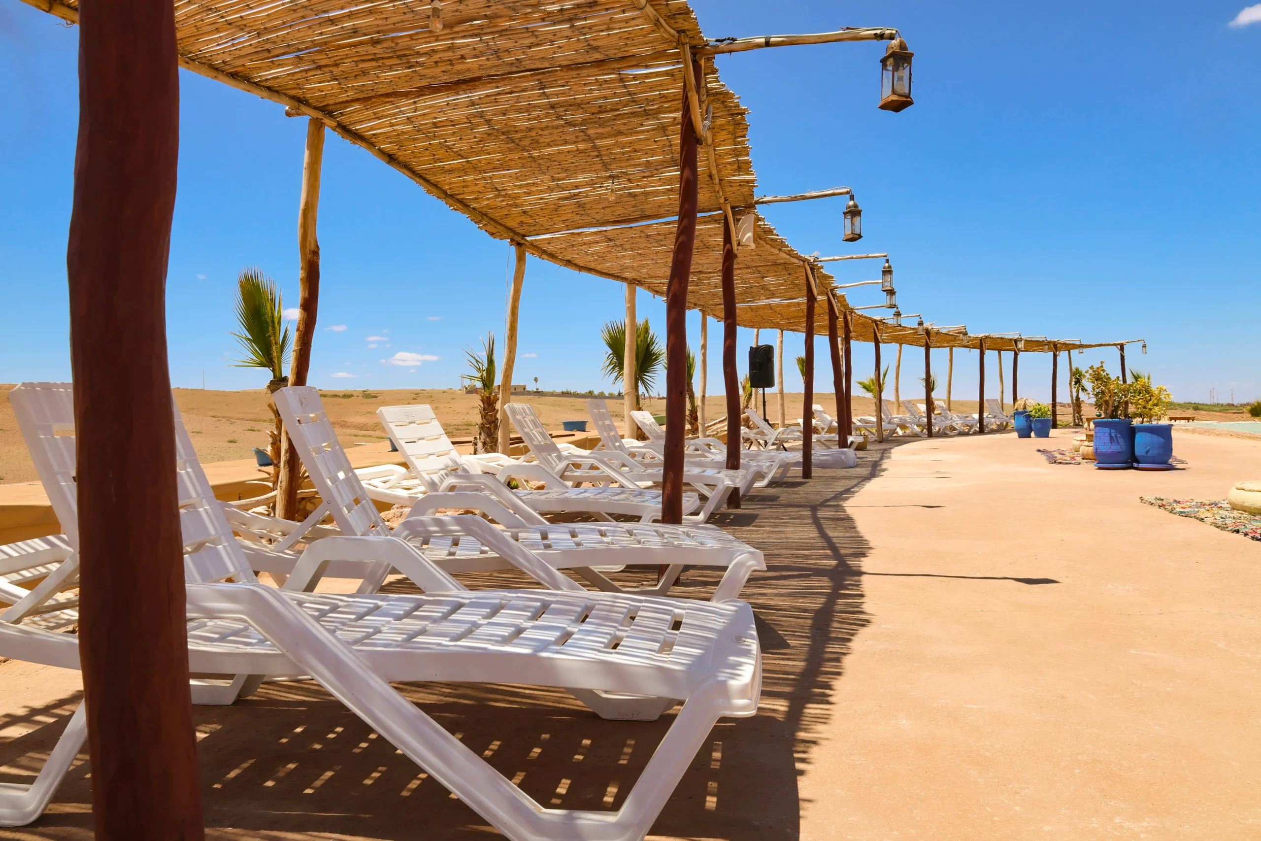 Sun loungers under a bamboo pergola in the Agafay Desert with clear blue sky