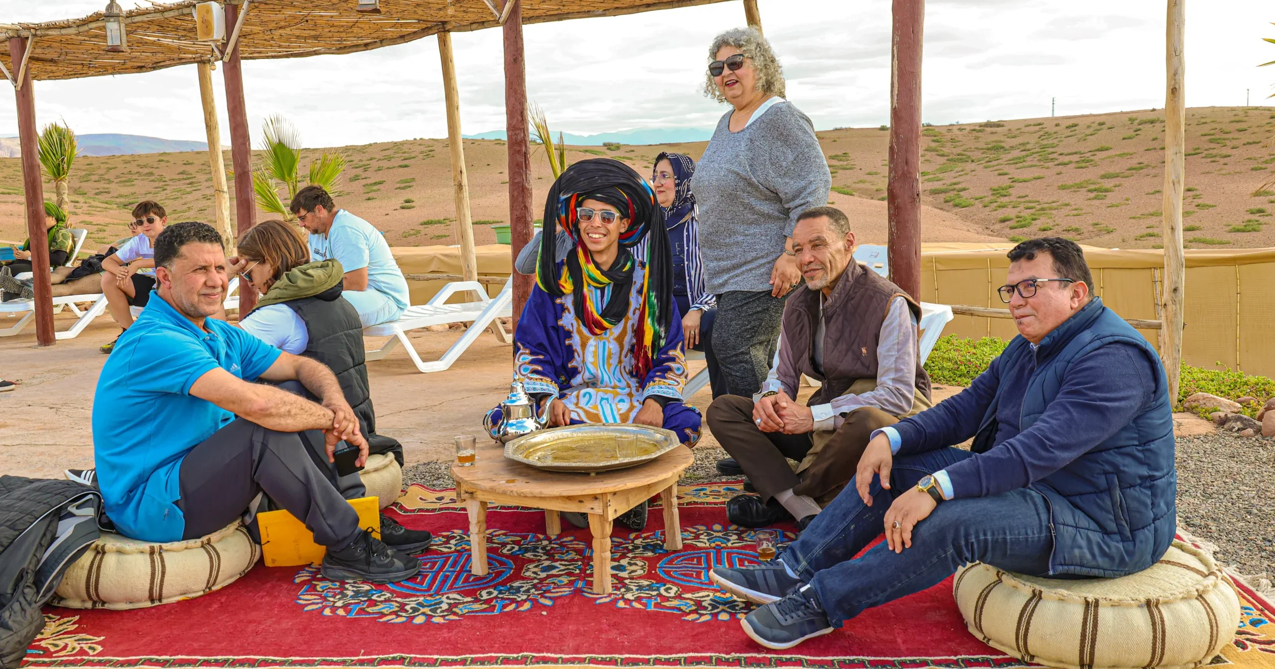 Traditional Moroccan tea ceremony in Agafay Desert with tourists under bamboo pergola